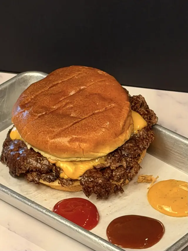 A double smash burger on a brioche bun with house made pickles, made in the Butcher's Pantry kitchen